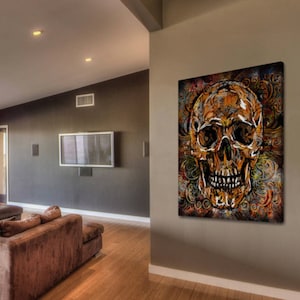 May include: A colorful abstract painting of a skull with intricate details. The skull is painted in shades of gold, brown, and red, and is surrounded by swirling patterns. The painting is set against a dark background.