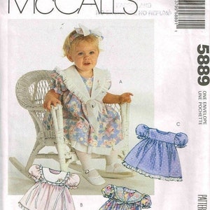 Puede incluir: Un patrón de costura para un vestido de niña bebé. El patrón incluye cuatro estilos diferentes de vestidos, todos con un dobladillo con volantes. El patrón es de McCall's y es para la talla 5889.