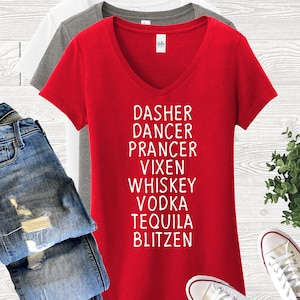 May include: Red V-neck t-shirt with white text that reads "Dasher Dancer Prancer Vixen Whiskey Vodka Tequila Blitzen". The shirt is paired with blue jeans and white sneakers.