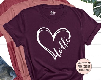May include: Burgundy t-shirt with a white heart and the name "Holli" written inside the heart. The shirt is layered over a pink t-shirt and a maroon t-shirt. The text "Hello Handpressed" is visible in the bottom right corner of the image.