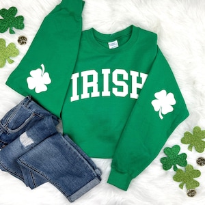 May include: Green sweatshirt with white shamrock designs on the sleeves and the word "IRISH" in white on the front.
