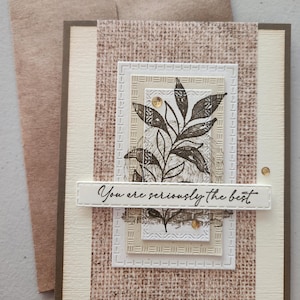May include: A handmade greeting card with a brown and beige color scheme. The card features a textured background, a floral design, and the phrase "You are seriously the best." An envelope is included.