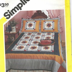May include: Simplicity sewing pattern number 6145 for a quilt with a starburst design. The quilt is in shades of orange, blue, and white. The pattern includes instructions for making a bed skirt and two pillowcases.
