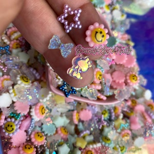 May include: A variety of colorful resin charms, including stars, flowers, and smiley faces. The charms are perfect for adding a touch of whimsy to crafts and nail art.