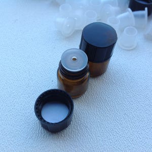 May include: Two amber glass bottles with black lids and white plastic droppers. The bottles are on a white surface.