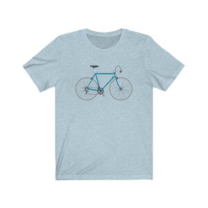 May include: A light blue bicycle with white tires and a black seat. The bicycle is on a light blue t-shirt.