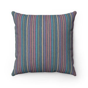 May include: A square throw pillow with a dark blue background and colorful vertical stripes. The stripes are in shades of pink, yellow, green, and blue.