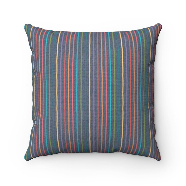 May include: A square throw pillow with a dark blue background and colorful vertical stripes. The stripes are in shades of pink, yellow, green, and blue.