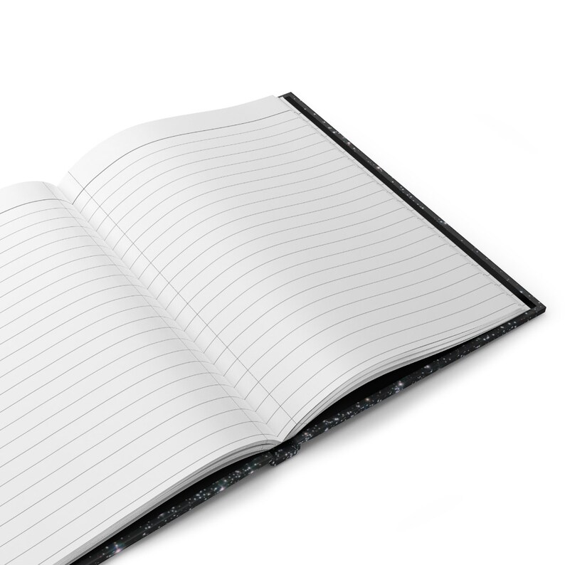 May include: A black notebook with a galaxy print cover. The notebook is open and has lined pages.