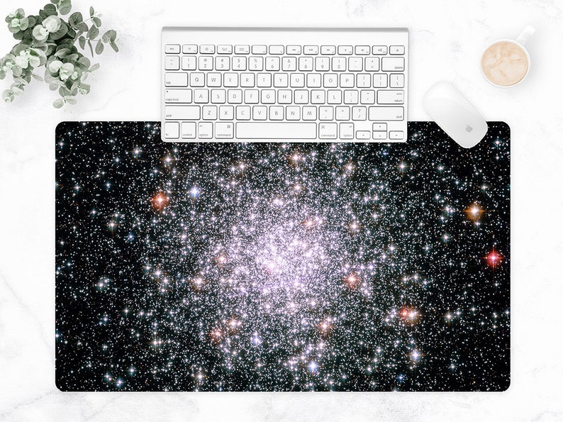 May include: A rectangular mouse pad featuring a vibrant image of a star cluster against a black background. A white keyboard and mouse are positioned above the pad, with a cup of coffee to the side. The pad measures approximately 30 inches long.