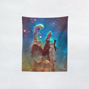 May include: A tapestry featuring a vibrant depiction of the Pillars of Creation, a nebula in the Eagle Nebula. The image showcases towering columns of gas and dust in shades of brown, yellow, and blue, with numerous bright stars scattered throughout.