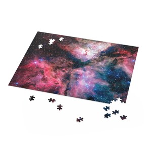 May include: A partially completed jigsaw puzzle depicting a colourful nebula with pink, blue, and purple shades. The puzzle pieces are scattered around the main image.