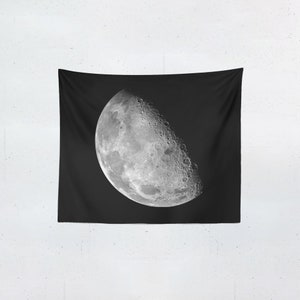 Puede incluir: Un tapiz negro con una imagen detallada de la luna en su fase creciente. La luna est&aacute; representada en tonos grises y blancos, mostrando cr&aacute;teres y detalles de la superficie sobre un fondo oscuro.