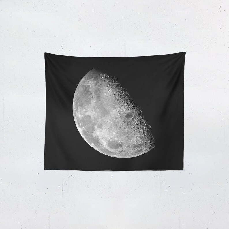 Puede incluir: Un tapiz negro con una imagen detallada de la luna en su fase creciente. La luna est&aacute; representada en tonos grises y blancos, mostrando cr&aacute;teres y detalles de la superficie sobre un fondo oscuro.