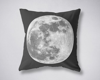 May include: A decorative throw pillow featuring a detailed grayscale image of the moon. The moon is centered on a dark gray pillow, showcasing its craters and textures. The pillow is square-shaped, perfect for adding a celestial touch to any room.