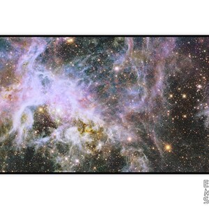 Puede incluir: Alfombrilla de escritorio rectangular con una imagen vibrante de una nebulosa con remolinos p&uacute;rpuras, azules y dorados. La alfombrilla tiene un borde negro y las palabras "EARTH MOON STARS" en blanco en la parte inferior derecha.