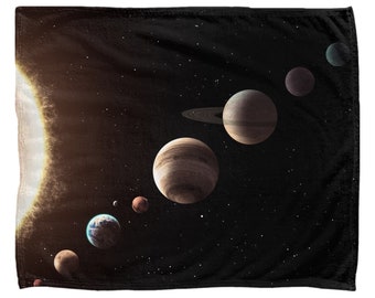 May include: A black fleece blanket with a colorful image of the solar system. The sun is in the lower left corner, and the planets are arranged in a line across the top of the blanket. The planets are in order from the sun: Mercury, Venus, Earth, Mars, Jupiter, Saturn, Uranus, and Neptune.