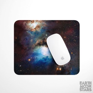 May include: A mousepad with a colorful nebula image. The nebula is a mix of blue, purple, and red hues with a white star in the center. The mousepad is on a white surface.
