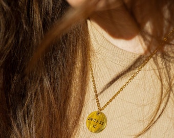 May include: A gold necklace with a round pendant that says "24.03.22" with a small heart symbol.