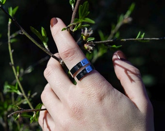 May include: Two silver rings with engraved designs. The top ring has a heart design and the bottom ring has a star design.