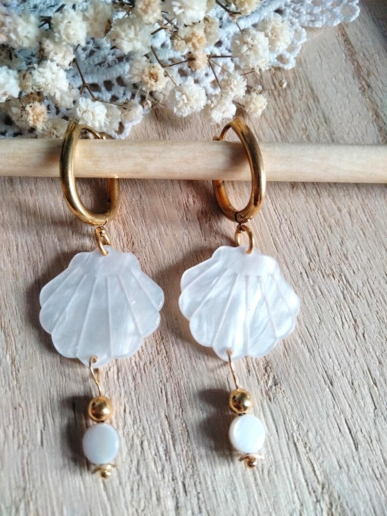 May include: Gold hoop earrings with white shell charms and white pearl accents.