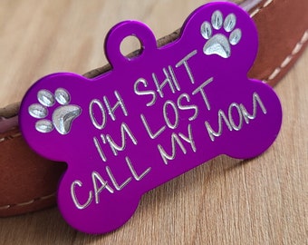May include: Purple bone-shaped dog tag with silver paw prints and the text "OH SHIT I'M LOST CALL MY MOM".