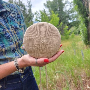 Round base of handmade crochet purse shown in hand
 Bottom view of mini tote bag in recycled cotton