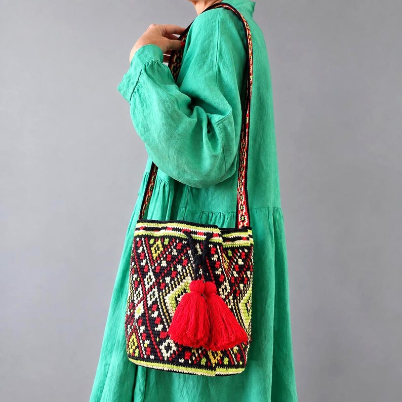 Woman wearing a handmade Ukrainian folk crochet shoulder bag with red tassels and geometric pattern.