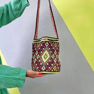 Handmade crochet bucket bag with Ukrainian folk pattern, red tassels and long woven shoulder strap.