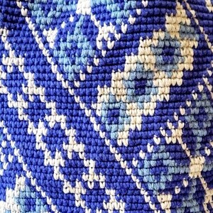 Close-up of handmade crochet stitches and blue geometric folk-inspired pattern