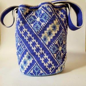 Back view of blue crochet bucket bag showing geometric woven pattern and wide shoulder strap