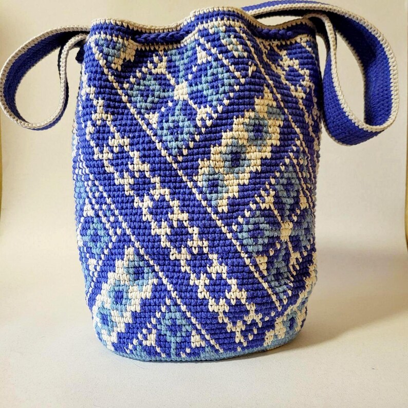 Back view of blue crochet bucket bag showing geometric woven pattern and wide shoulder strap