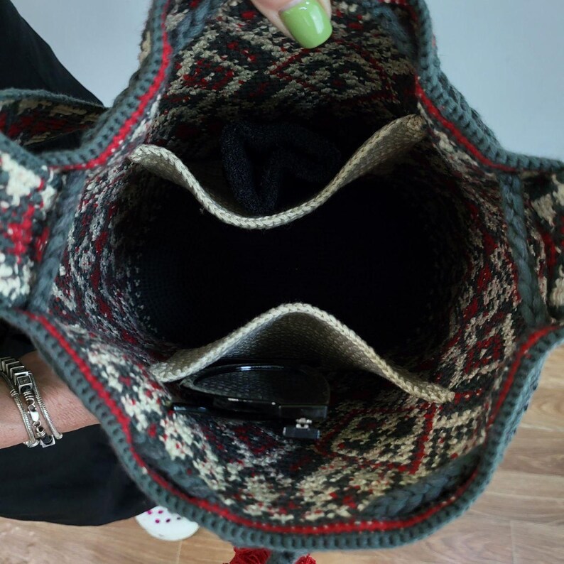 May include: A green, red, and white patterned crocheted bag with a zippered pocket and a drawstring closure. The bag is open and shows the inside lining.