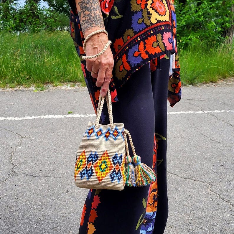 Crochet women  handbag shown in hand with colorful tassels
Handmade cross body purse displayed outdoors in natural light