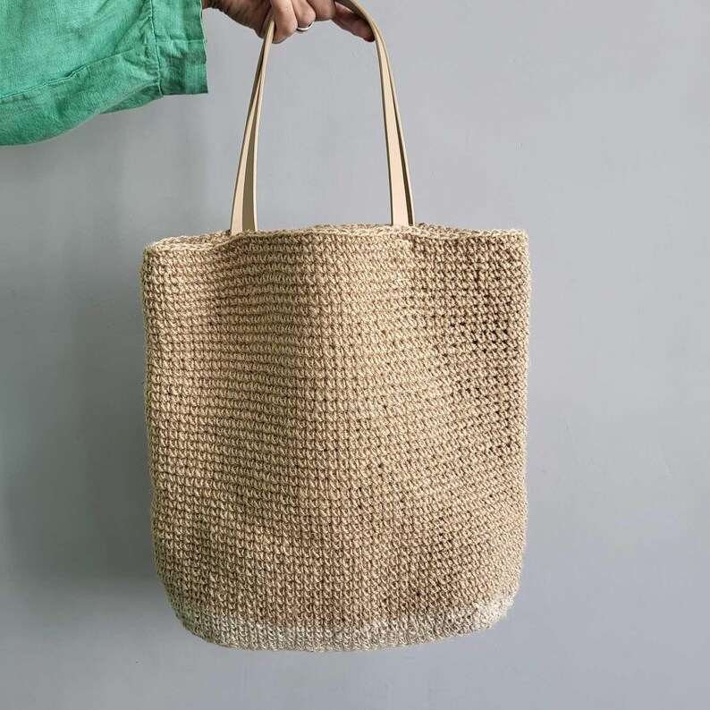 Back view of handmade jute crochet tote bag showing the simple natural woven design and faux leather straps.