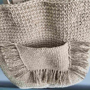 Close-up of the exterior crochet pocket with jute fringe on the front of the handmade tote bag.