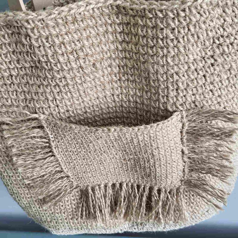 Close-up of the exterior crochet pocket with jute fringe on the front of the handmade tote bag.