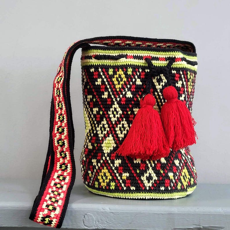 Crochet shoulder bag with red tassels, colorful Ukrainian inspired geometric pattern and drawstring closure.