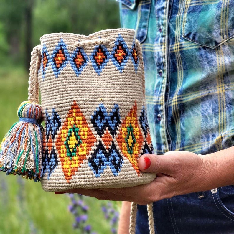 Woven phone pouch displayed between two hands outdoors
 Compact crochet handbag showing bucket bag proportions
