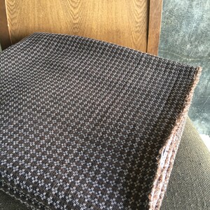May include: A brown fabric with a white pattern of small stars. The fabric has a fringed edge.