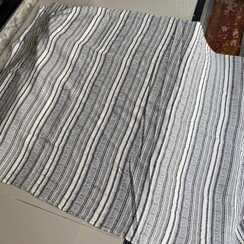 May include: A white and gray striped throw blanket with a textured weave.