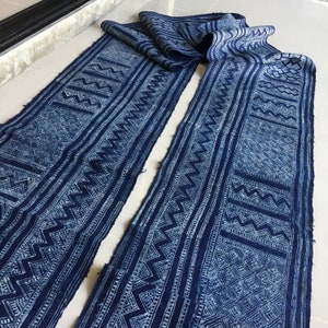 May include: Two long strips of indigo blue fabric with a white geometric pattern. The fabric is folded in half and the pattern is visible on both sides.