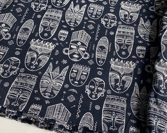Puede incluir: Tela negra con un patrón blanco repetitivo de máscaras africanas estilizadas. Las máscaras están delineadas en blanco y tienen detalles intrincados.