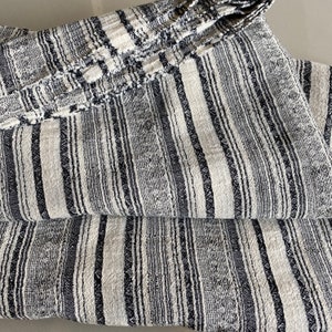 May include: A black and white striped fabric with a textured weave. The fabric is folded in thirds, showing the pattern.