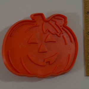 May include: Orange plastic pumpkin cookie cutter with a carved jack-o'-lantern face.