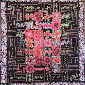 Puede incluir: Una colcha con fondo negro y un patrón de amapolas rojas y hojas verdes. La colcha está enmarcada con un borde paisley morado y negro.