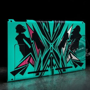 May include: A turquoise Nintendo Switch console with a black and pink graphic design featuring stylised figures and geometric shapes. The design includes the text "XL Team".