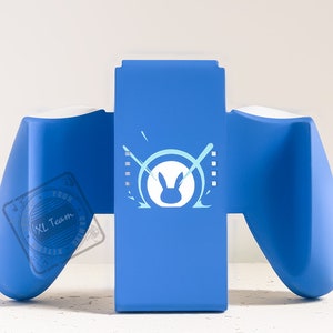Könnte beinhalten: Blau-weißer Videospiel-Controller mit einem blauen Ständer. Der Ständer hat ein weißes Kaninchenlogo mit einem Kreis darum und zwei gekreuzten Stöcken dahinter.