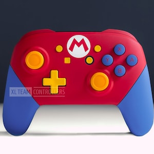 May include: A red and blue Nintendo Switch controller with a yellow plus sign, yellow circles, and a white Mario logo. The text "XL TEAM CONTROLLERS" is printed on the controller.