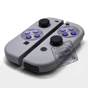 May include: A gray Nintendo Switch controller with purple and blue buttons. The controller has a retro design inspired by the Super Nintendo Entertainment System (SNES).